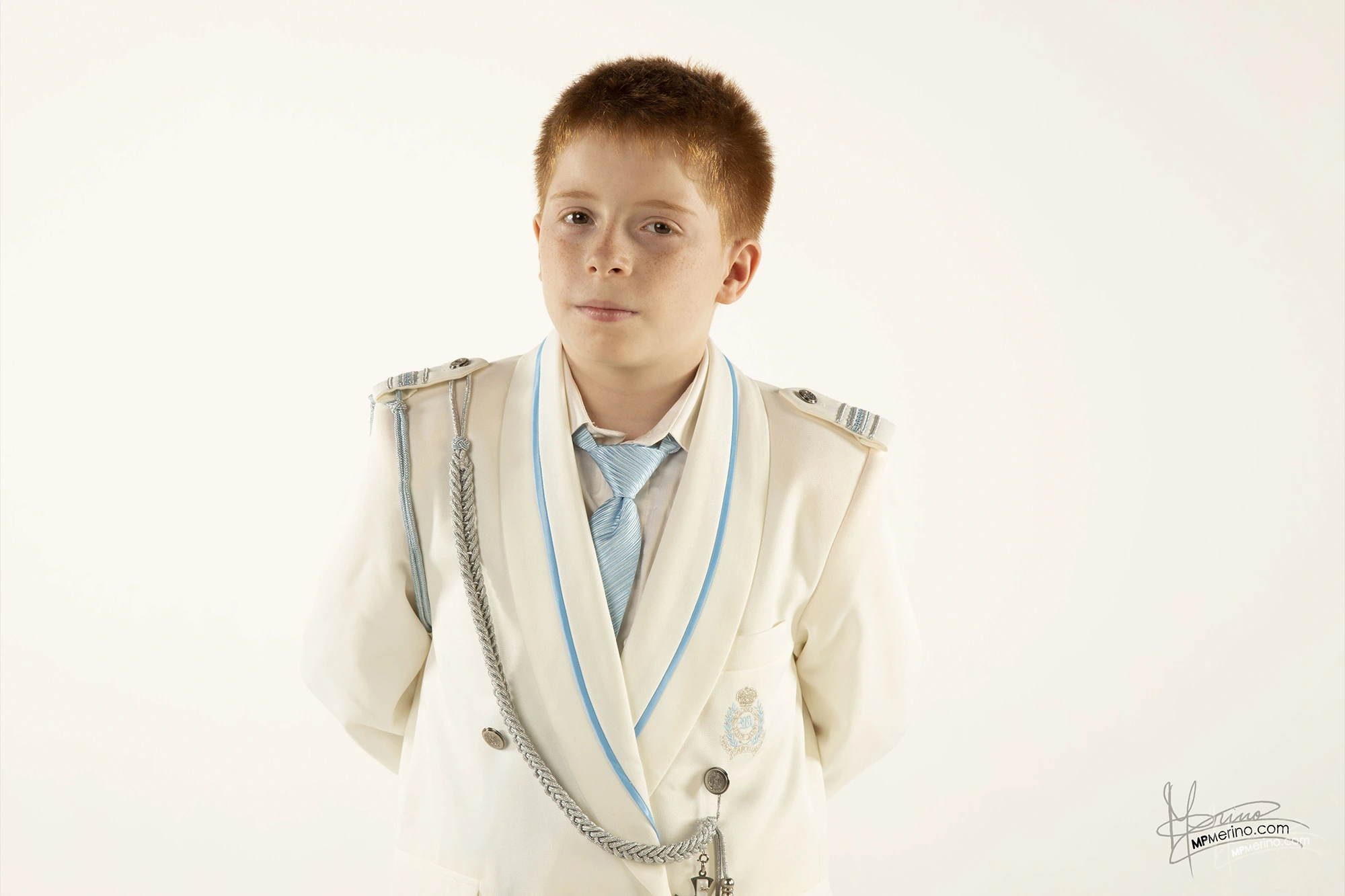 Studio photograph of a child in communion suit looking at the camera