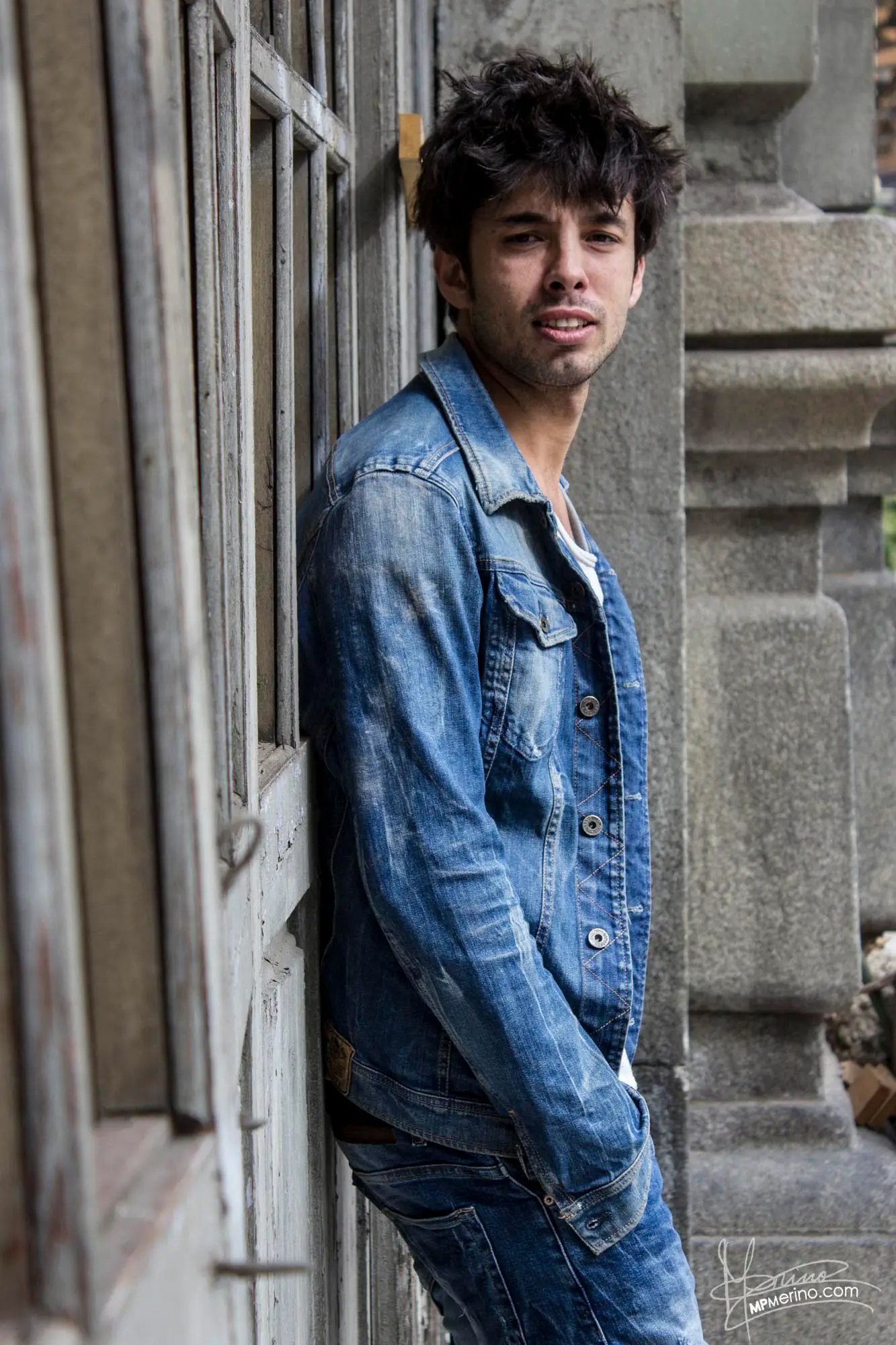 Half-body photograph of a boy leaning against the wall of an abandoned building