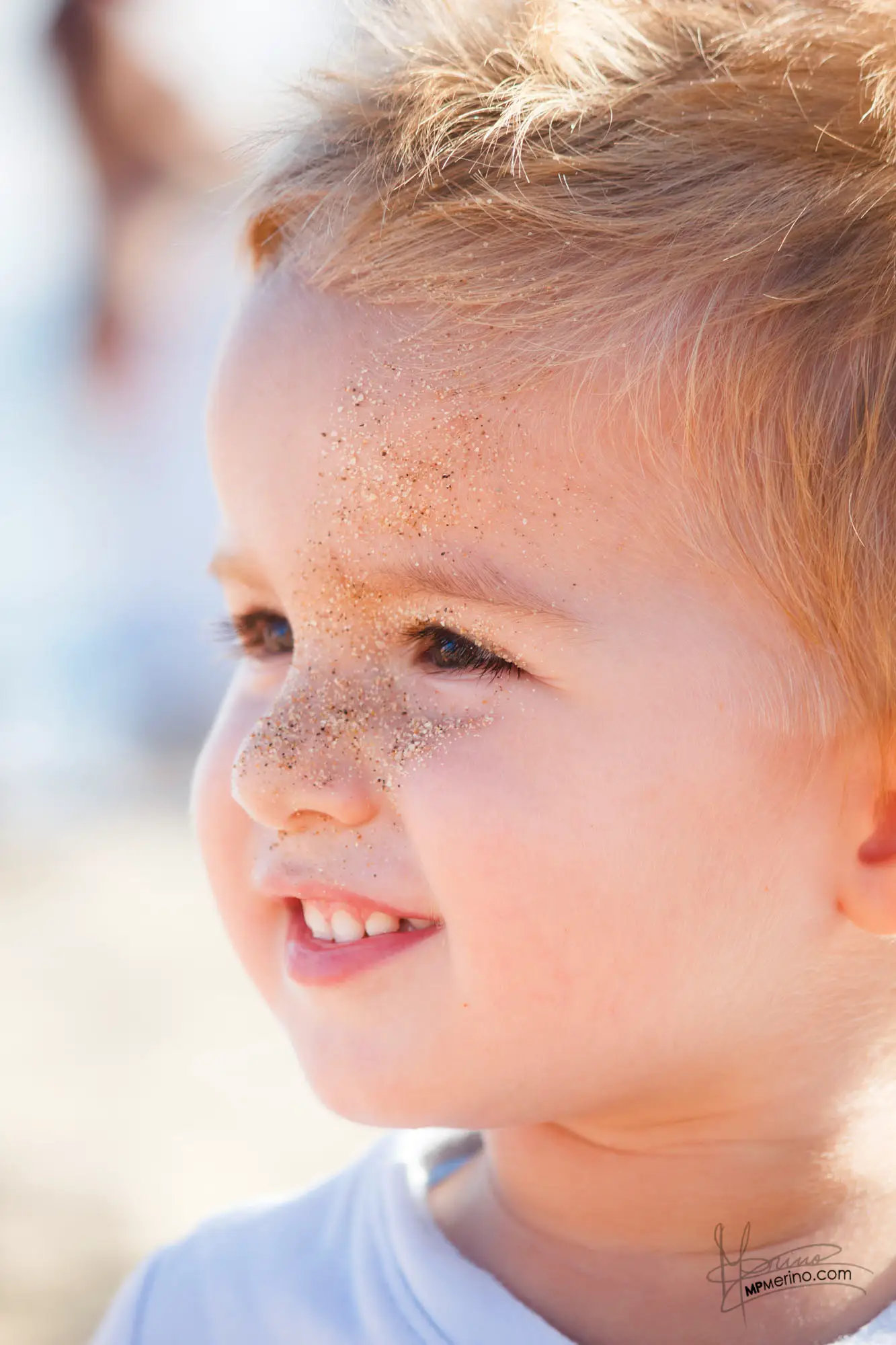 Portrait of a small child smiling with sand on his face