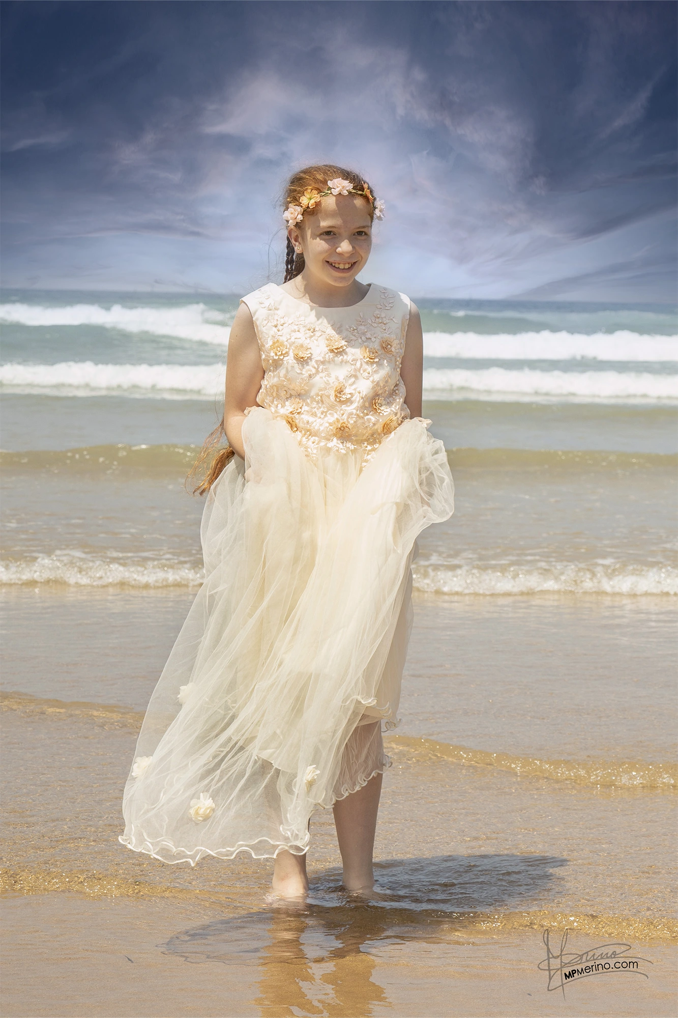 A girl holds her communion dress on the beach