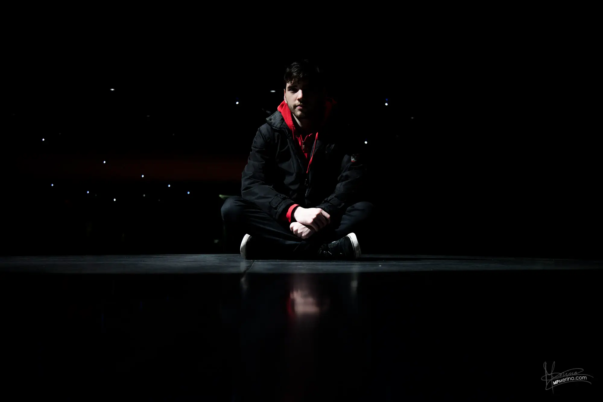 Photograph of a boy sitting on the floor of a shopping centre looking at the camera