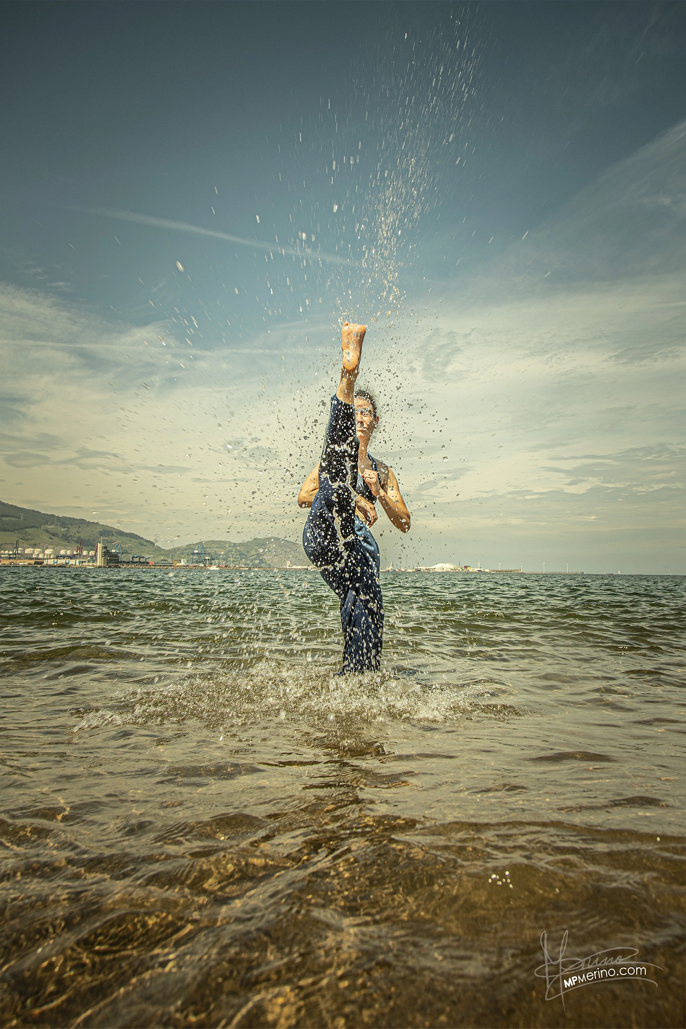 Photo of a Taekwondo coach kicking from the water on the beach